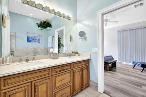 a bathroom with a sink and a large mirror at CocoBreeze - Poolside Paradise Mins to Beach! in Naples