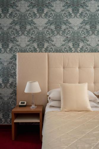 a bedroom with a bed and a table with a lamp at Albergo Rossini 1936 - Small & Charming in Bologna