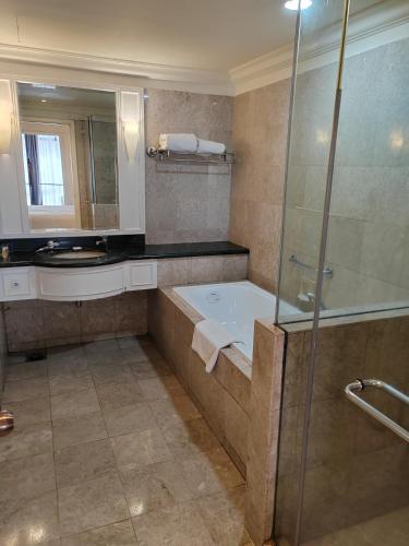a bathroom with a tub and a glass shower at Kl Continew Suite At Times Square in Kuala Lumpur