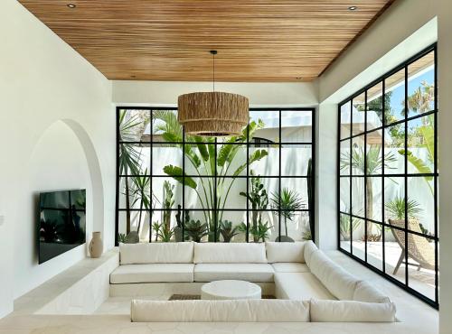 a living room with a white couch and large windows at Melrose x The Young Villas in Uluwatu