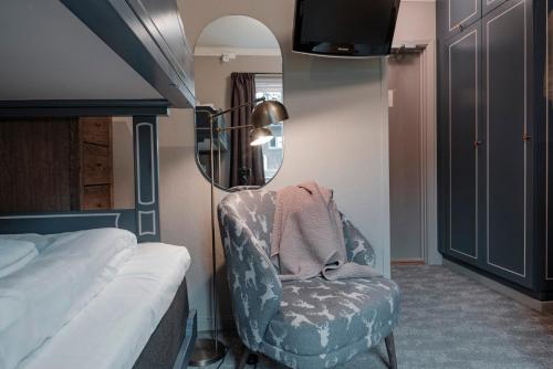 a bedroom with a chair and a mirror and a bed at Trillevallens Högfjällshotell & Lägenheter in Trillevallen