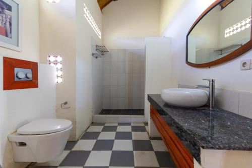 a bathroom with a toilet and a sink and a mirror at Vedanta Villa in Lovina