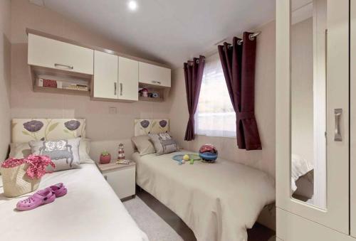 Habitación pequeña con 2 camas y ventana en Lagooncombe, modern and cosy (Wi-Fi & Fire Stick) en Millom