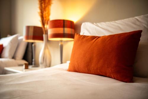 een bed met een oranje kussen en een bank bij Stag Manor Hot Tub Retreat near Peak District in Crich