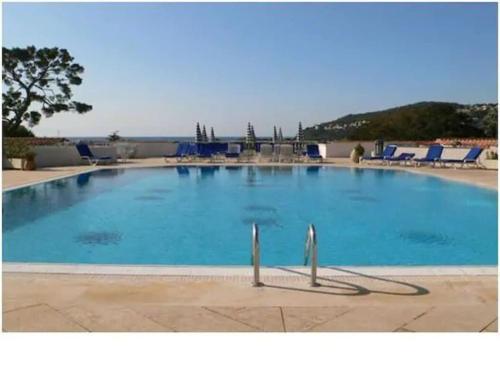 a large blue swimming pool with blue lounge chairs at Pool , 150m to beach, seaview in Villefranche-sur-Mer
