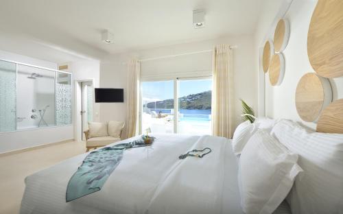 a white bedroom with a large bed with a view of the ocean at Nissaki Boutique Hotel in Platis Yialos Mykonos