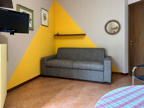 a couch in a room with a yellow wall at VIASANMARCO12.APT in Torre deʼ Busi