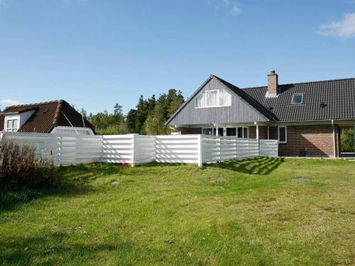 una cerca blanca frente a una casa en 8 person holiday home in H jslev, en Bøstrup