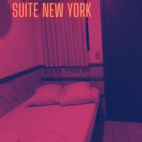 a bed in a room with pink lights and a sign at New York in Juiz de Fora