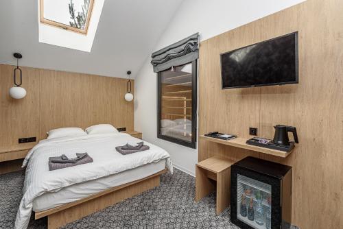 ein Schlafzimmer mit einem Bett, einem Kamin und einem TV in der Unterkunft Molėtairesort in Molėtai