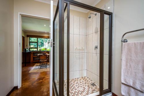 a bathroom with a shower with a glass door at Kuhestan Farm Cottages in Haenertsburg