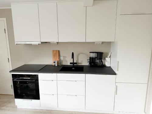 a kitchen with white cabinets and a black counter top at Tromsdalen Aurora Apartments in Tromsø