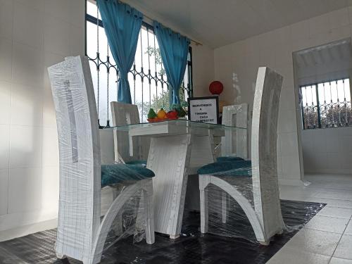 a glass table with two white chairs around it at Yinkana Camping y Glamping in Guatavita