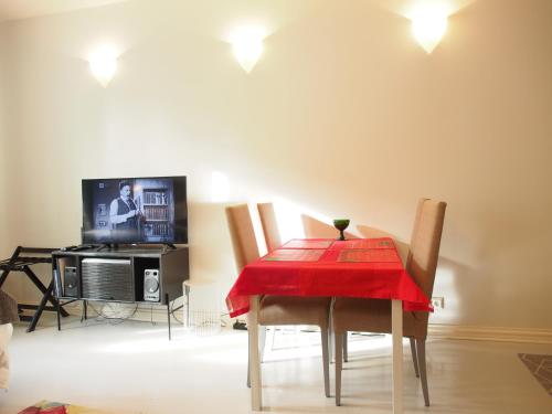 a dining room with a red table and chairs and a tv at Top Apartments Helsinki - Alppila in Helsinki
