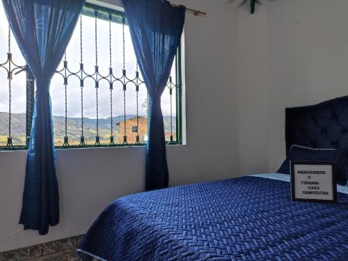 a bedroom with a bed and a window with blue drapes at Yinkana Camping y Glamping in Guatavita