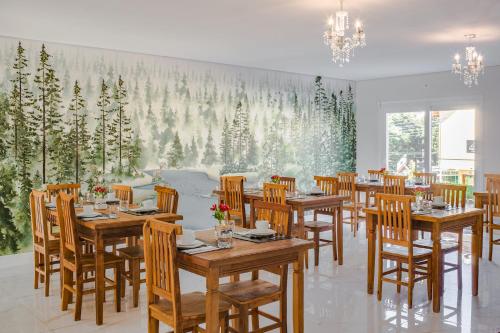 a restaurant with wooden tables and chairs and a large mural at Altitude Lodge Hotel in Campos do Jordão