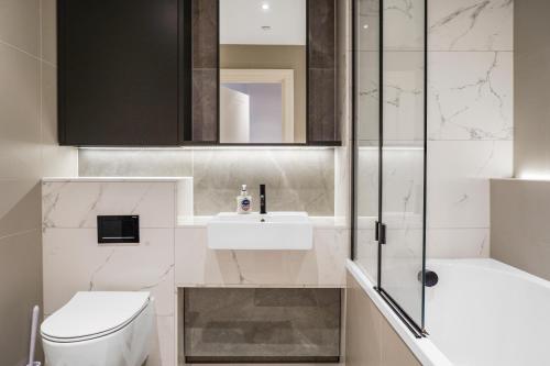 a bathroom with a toilet and a sink and a shower at Utopian Apartments Kilburn in London