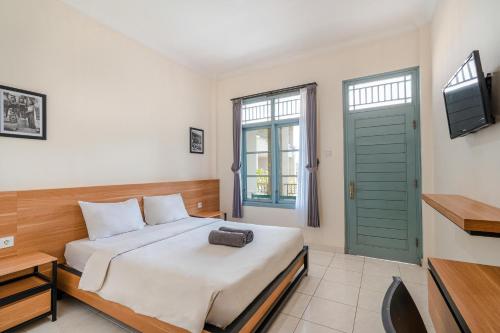 1 dormitorio con 1 cama con puerta verde y TV en Pondok Anyar Hotel, en Kuta