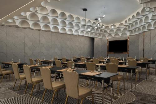 a dining room with tables and chairs and a screen at SO/ Uptown Dubai in Dubai