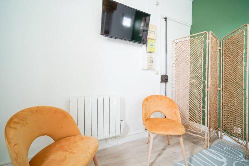 Cette chambre dispose de 2 chaises et d'une télévision murale. dans l'établissement Green studio cosy and confortable - III, à Paris