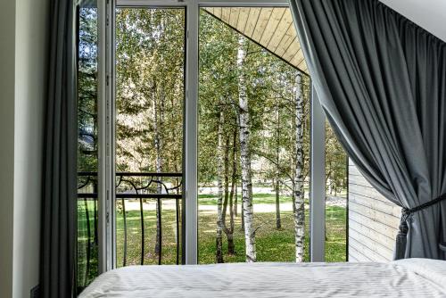 una camera da letto con una grande finestra che guarda gli alberi di Miško Spa namas a Molėtai