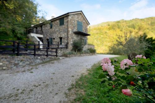 a stone house on a gravel road with pink flowers at Il Mulino - Appartamento Terra in Borzonasca