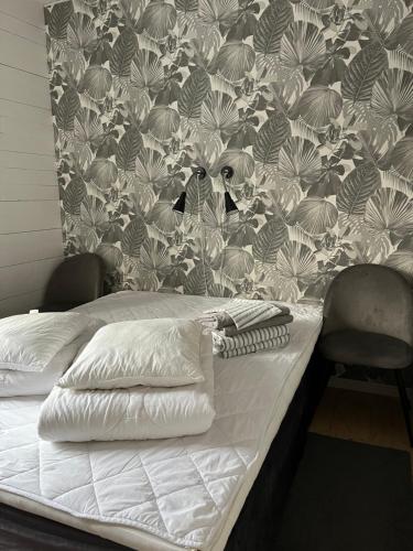 1 cama con sábanas blancas y pared con papel pintado en Vintergatans Rum, en Insjön