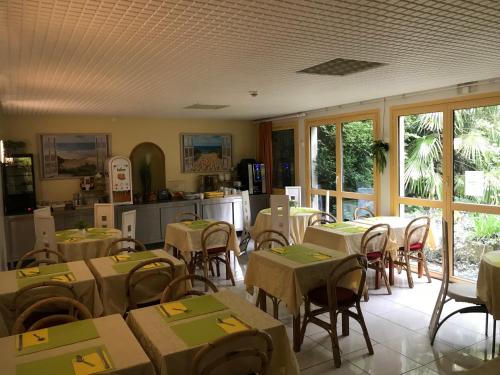 a restaurant with tables and chairs and a kitchen at Hotel Bar Restaurant Couleurs Sud in Charleville-M&eacute;zi&egrave;res