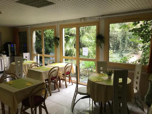 a dining room with tables and chairs and windows at Hotel Couleurs Sud Centre-ville Gare Charleville-Mézières in Charleville-Mézières