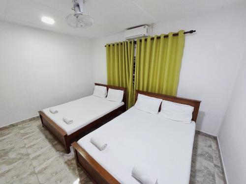 two beds in a room with a green curtain at HOSTEL KATUNAYAKE At COLOMBO AIRPORT TRANSIT in Katunayake