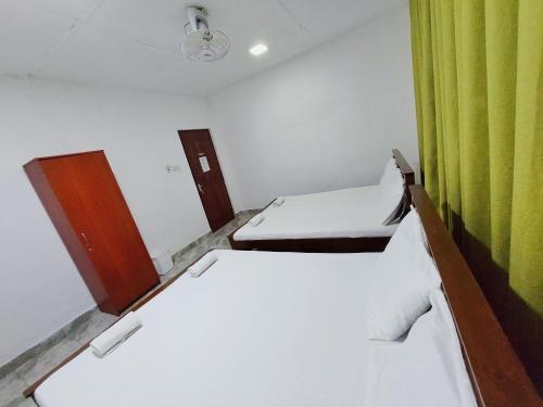 a room with two beds and a green curtain at HOSTEL KATUNAYAKE At COLOMBO AIRPORT TRANSIT in Katunayake