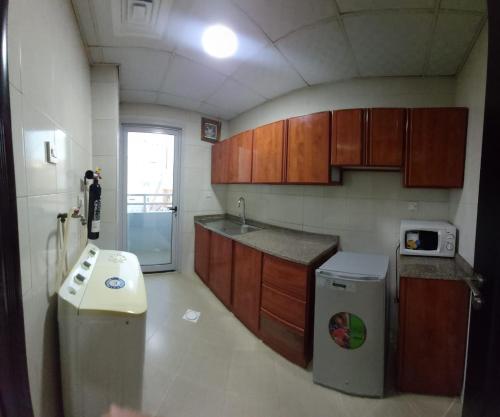 a kitchen with a sink and a stove and a refrigerator at Al Khaleej Plaza Furnished Apartments LLC in Ajman 
