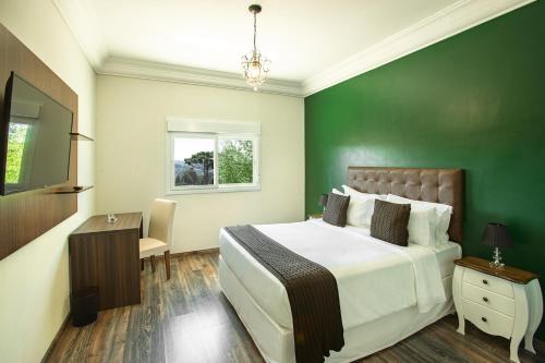 a bedroom with a large bed and a green wall at Altitude Lodge Hotel in Campos do Jordão