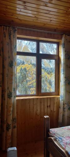 a room with a window in a log cabin at Guest House EMZAR in Adishi
