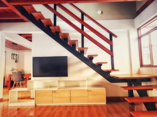 a living room with a tv and a staircase at Casa Belgrado, te espera. in Oxapampa