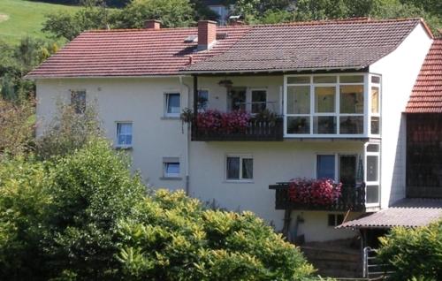 Casa blanca con balcón con flores. en Ferienwohnung Kraemer en Mossautal