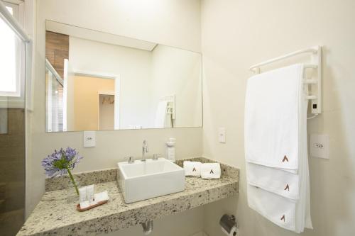 a white bathroom with a sink and a mirror at Altitude Lodge Hotel in Campos do Jordão