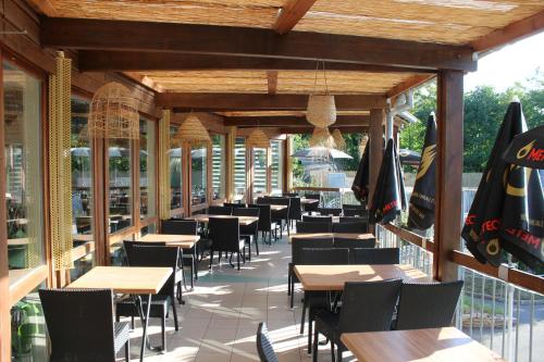 ein Restaurant mit Tischen und Stühlen auf einer Terrasse in der Unterkunft Camping les Acacias in Altkirch