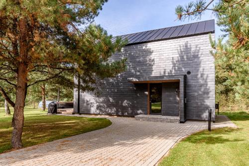 a gray brick building with a door in a park at Pirties Spa namas in Molėtai