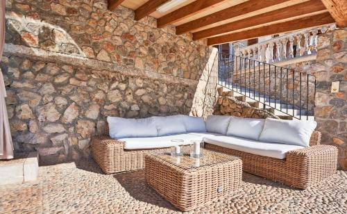 a patio with wicker furniture and a stone wall at Quiet Villa in Buger with amazing pool, paddle court and nice garden in Búger