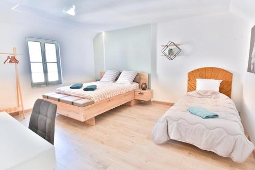 Le Speakeasy - Maison avec billard في أوكسير: سريرين في غرفة بجدران بيضاء وأرضية خشبية