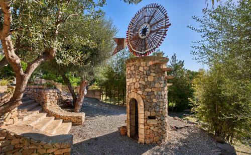 a stone structure with a clock on top of it at Quiet Villa in Buger with amazing pool, paddle court and nice garden in Búger