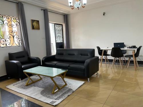 a living room with a black couch and a table at Appart meublé haut standing, WIFI, TV - Yaoundé, Omnisports in Yaoundé