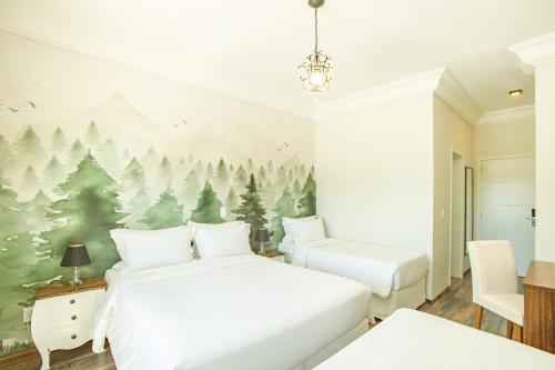 um quarto com 2 camas e um mural de árvores em Altitude Lodge Hotel em Campos do Jordão
