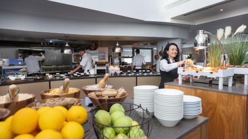 a woman standing in a kitchen preparing food at Hilton Cambridge City Centre in Cambridge
