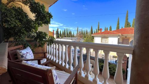 uma varanda com um corrimão branco e vista para uma casa em VILLA ROSARIO entre Granada y Sierra Nevada em La Zubia