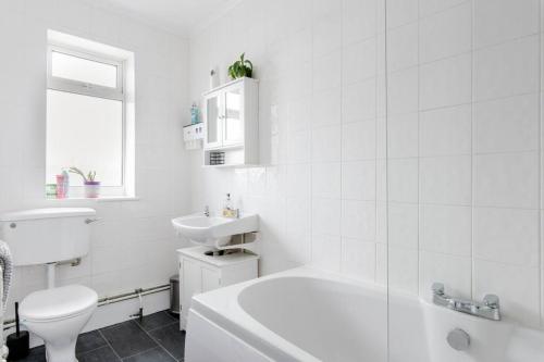 a white bathroom with a toilet and a sink at Lavender Lodge - Near Shops & with Free Parking in Haywards Heath