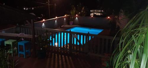 a swimming pool with lights on a fence at night at Bungalow Caraïbes, proche de la route mais calme la nuit. in Trois-Rivières