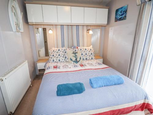 a bedroom with a bed with two blue pillows on it at Beachcomber D35 in Abergele