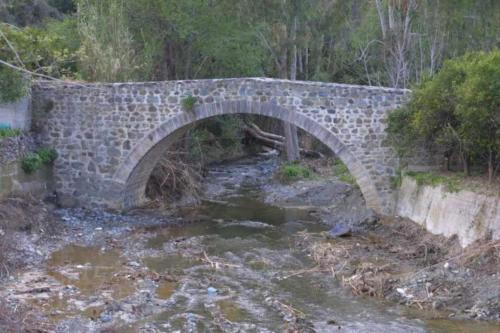 a stone bridge over a stream of water at Beautiful 3 Bedr House in Arakapas with fireplace in Arakapas